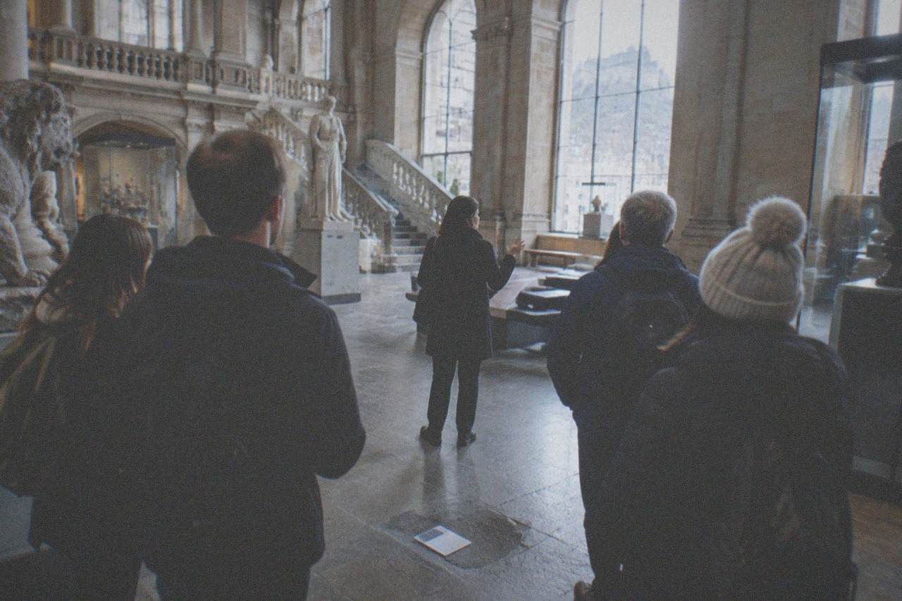 Grand museum hall with stone columns and visitors viewing exhibits