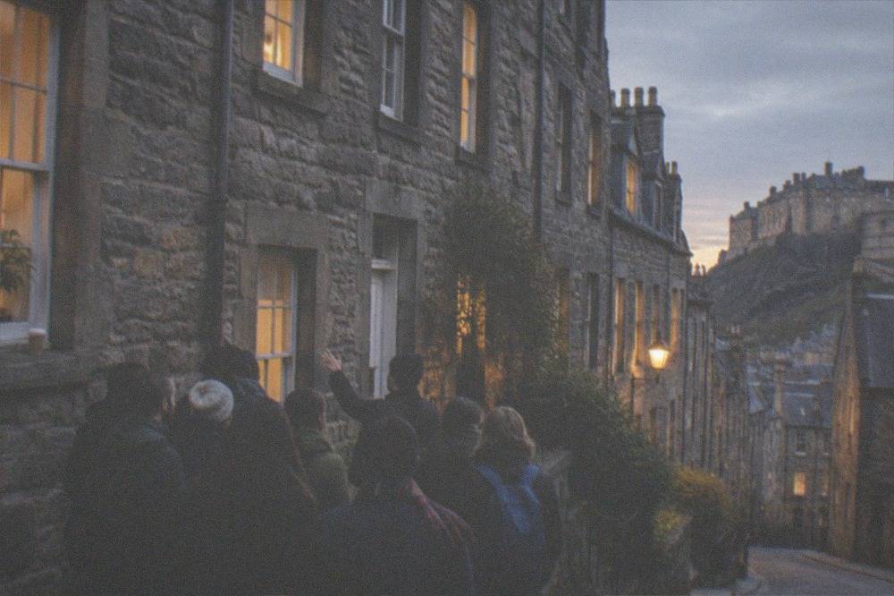Illuminated historic buildings and narrow close at dusk in Edinburgh