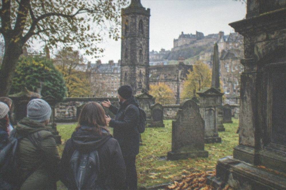 Greyfriars Kirkyard gravestones beneath a dark stone church tower in Edinburgh