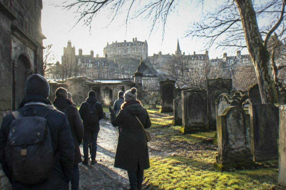 A stone close and old churchyard with the Edinburgh skyline rising behind