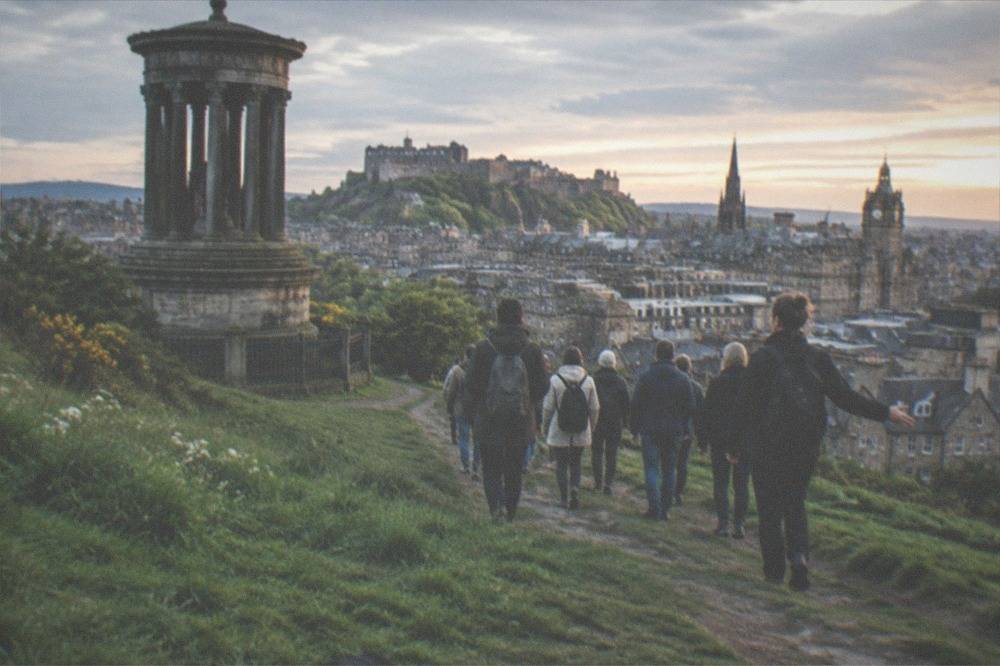 A green hill rising above city rooftops with a winding path to the summit