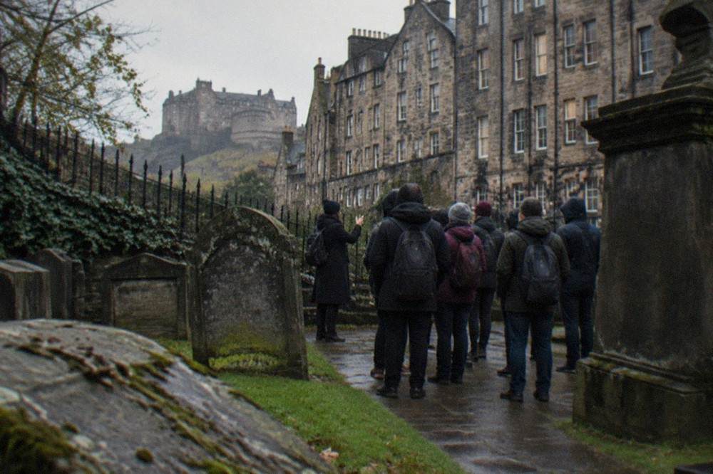Greyfriars Kirkyard gravestones with Edinburgh tenement buildings behind them under grey cloud