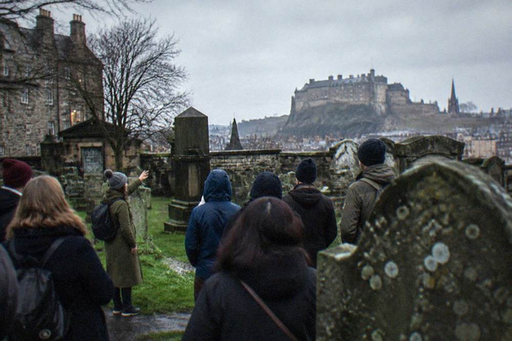 Grey gravestones and a stone wall in an old Edinburgh kirkyard under a grey sky