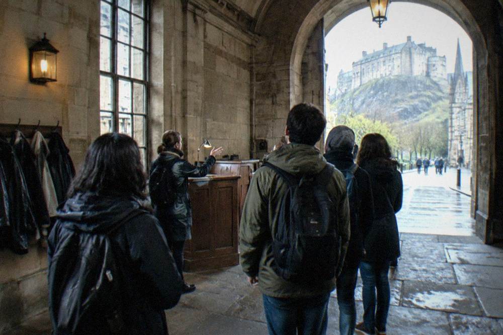 Museum entrance hall with stone archways, information desk and visitors' coats hanging on hooks