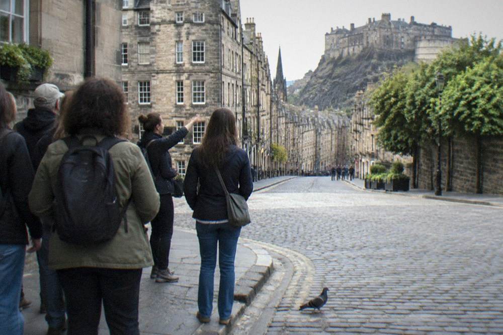 A guide speaking to a small group gathered on a stone street corner
