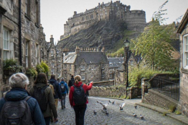 Weathered stone ramparts of Edinburgh Castle rising above the dark basalt crag, low cloud passing over the empty esplanade, rooftops falling away below.