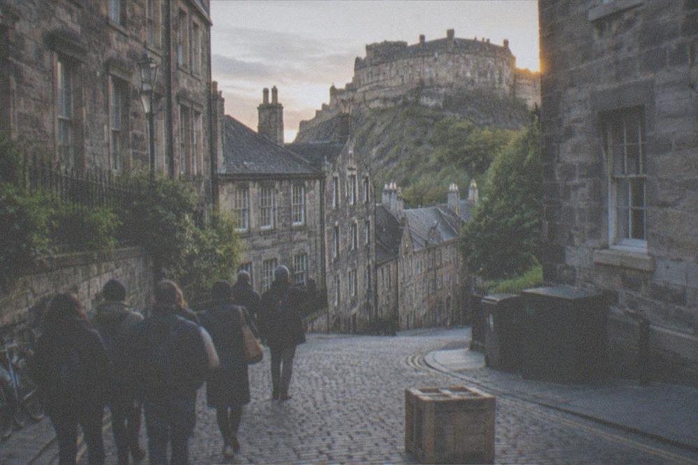 Cobbled Old Town street curving toward the castle with tenement buildings on both sides