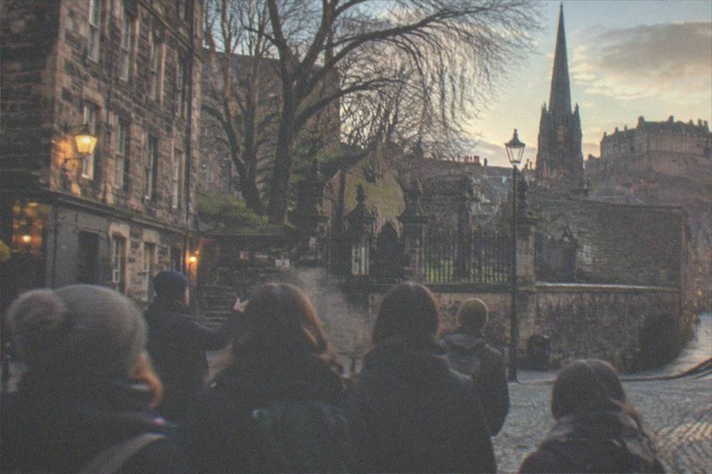 Old walled burial ground with mossy table-top tombs and a locked iron gate
