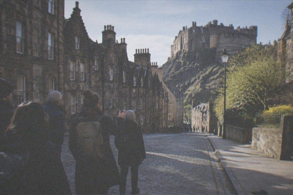 Castle rock rising above old town rooftops seen from a city street