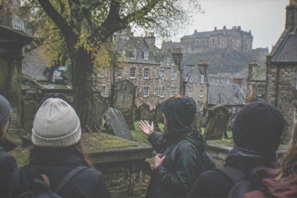 Grey gravestones and leafy trees inside Greyfriars Kirkyard below the Edinburgh skyline