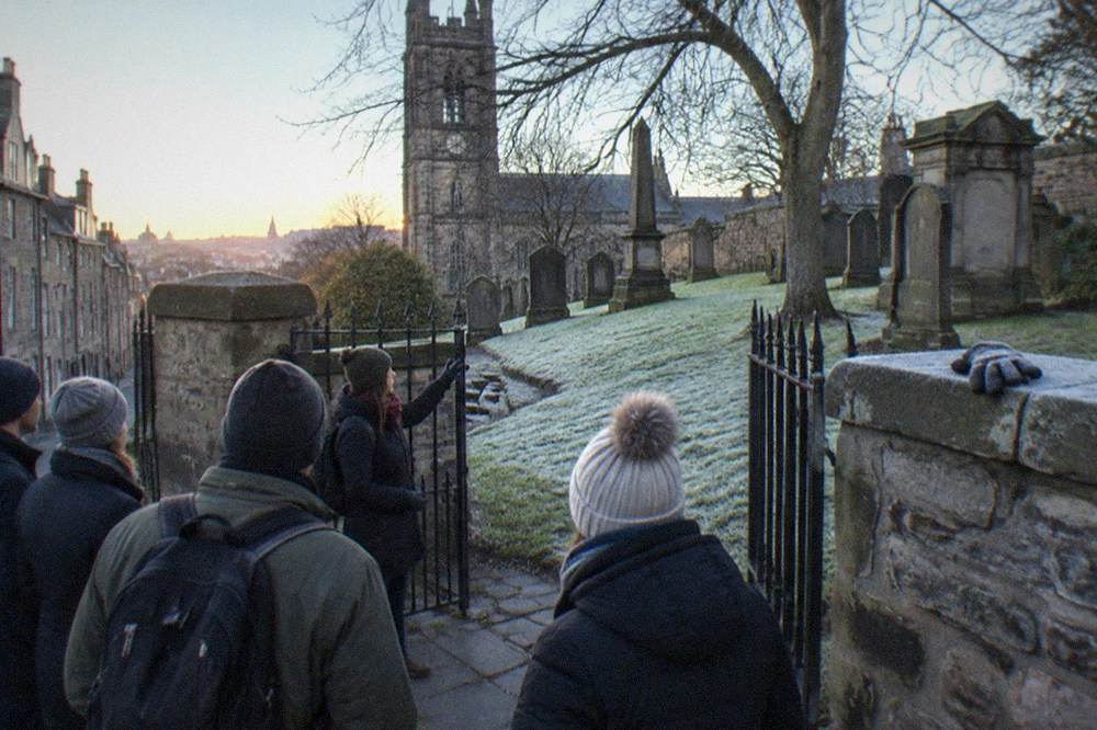 A historic graveyard with old stone monuments and a church tower behind