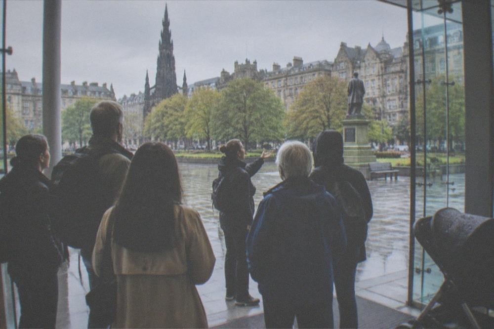 Visitors reading a museum information board inside a gallery in Edinburgh