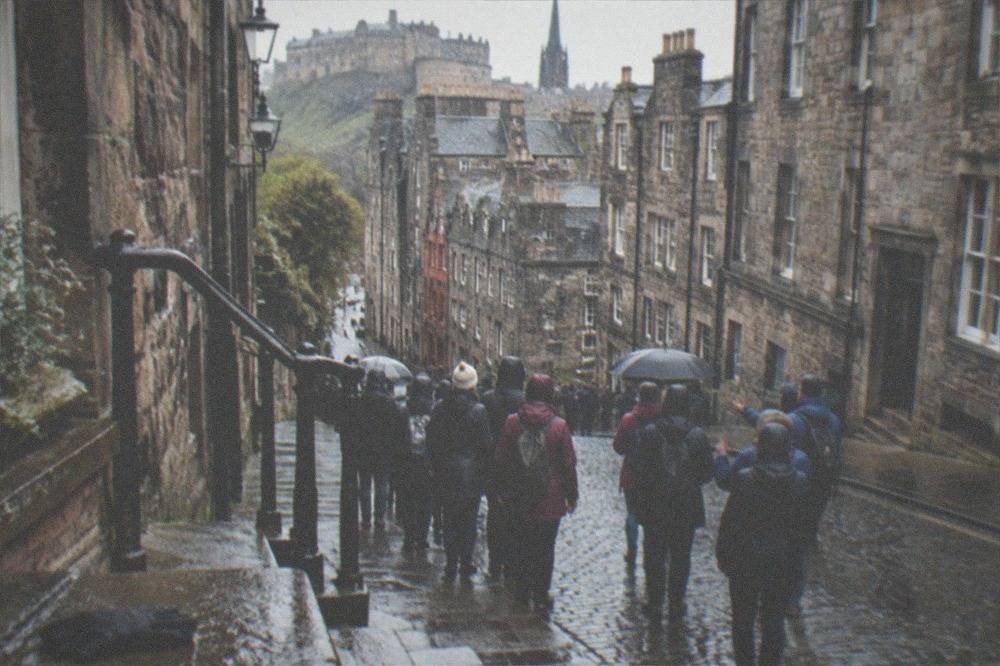 Narrow stone close descending between tall old buildings with wet steps and a lamp on the wall