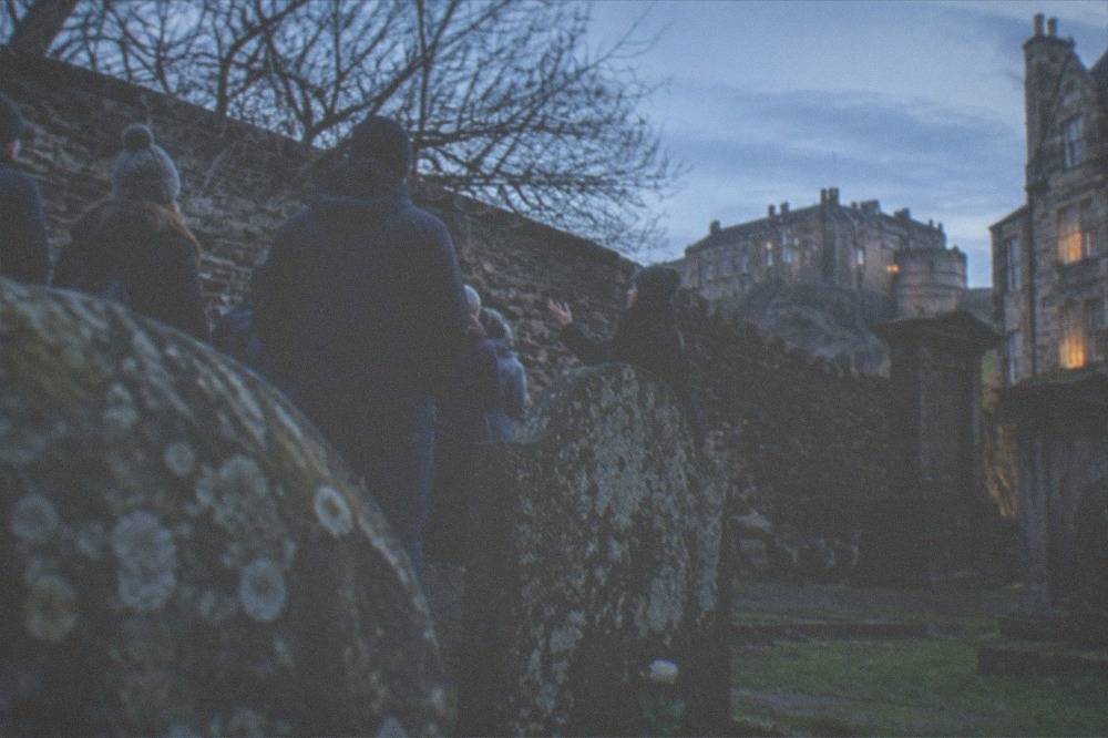 Old graveyard headstones and dark stone wall in evening light