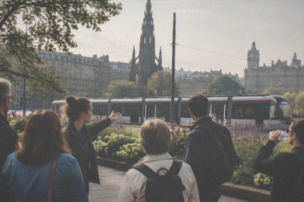 Tram travelling along a city street with stone buildings behind it