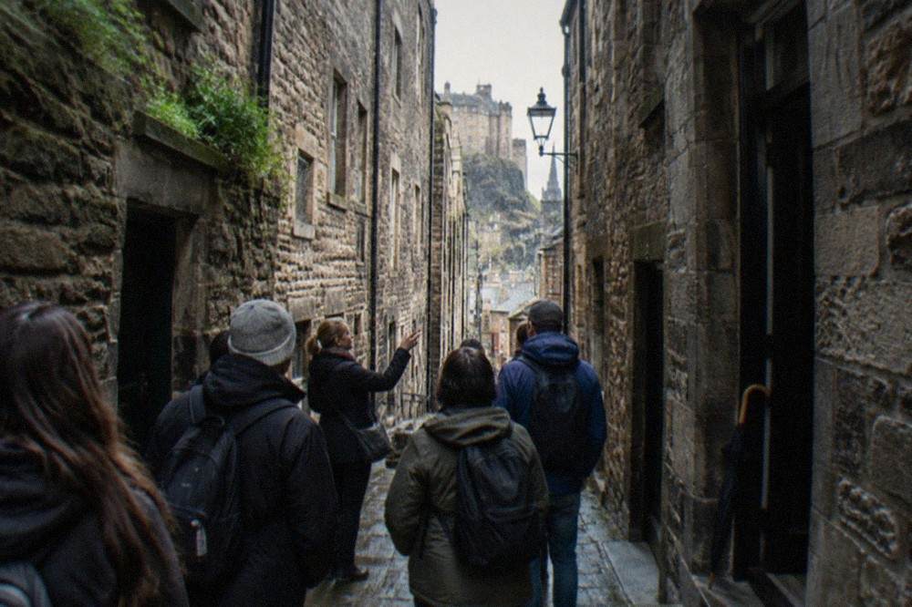 Narrow stone close in Edinburgh's Old Town with tall tenement walls rising on both sides