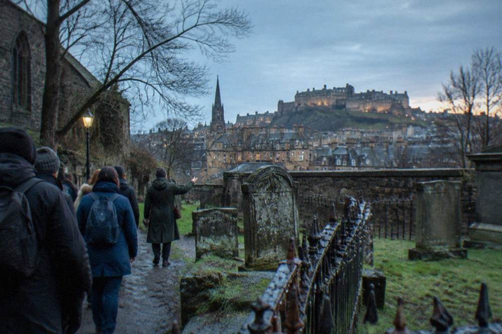 Greyfriars Kirkyard in Edinburgh with weathered gravestones and the city skyline behind