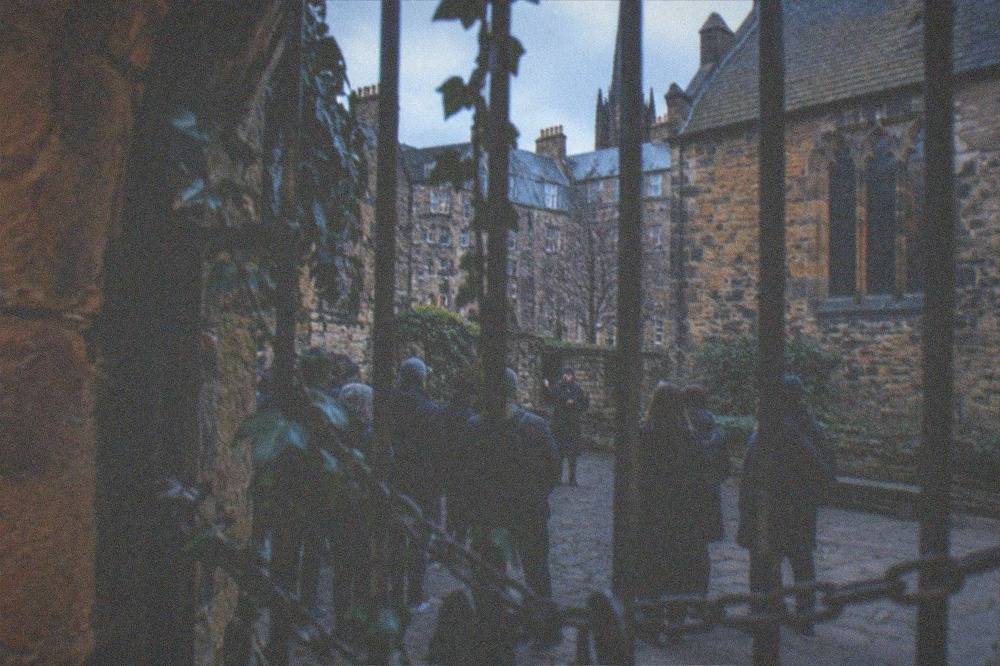 Iron gates chained across a stone archway leading into an old cemetery at dusk